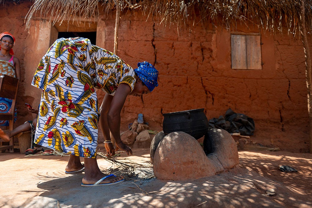 Adjoa putting kindling in a fire after cleft surgery