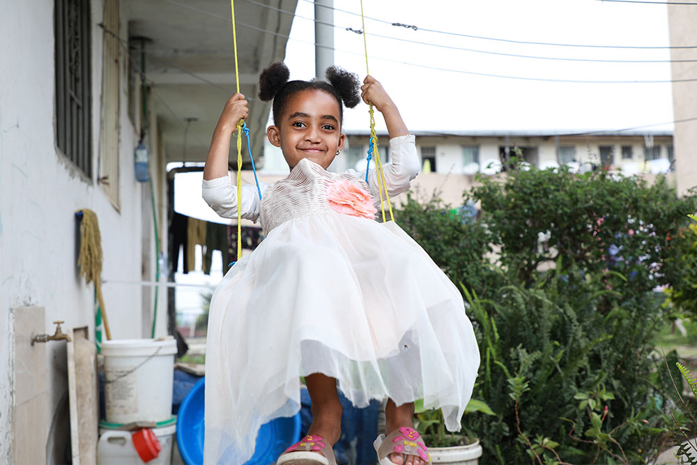 Marsillas smiling and swinging on a swing after cleft surgery