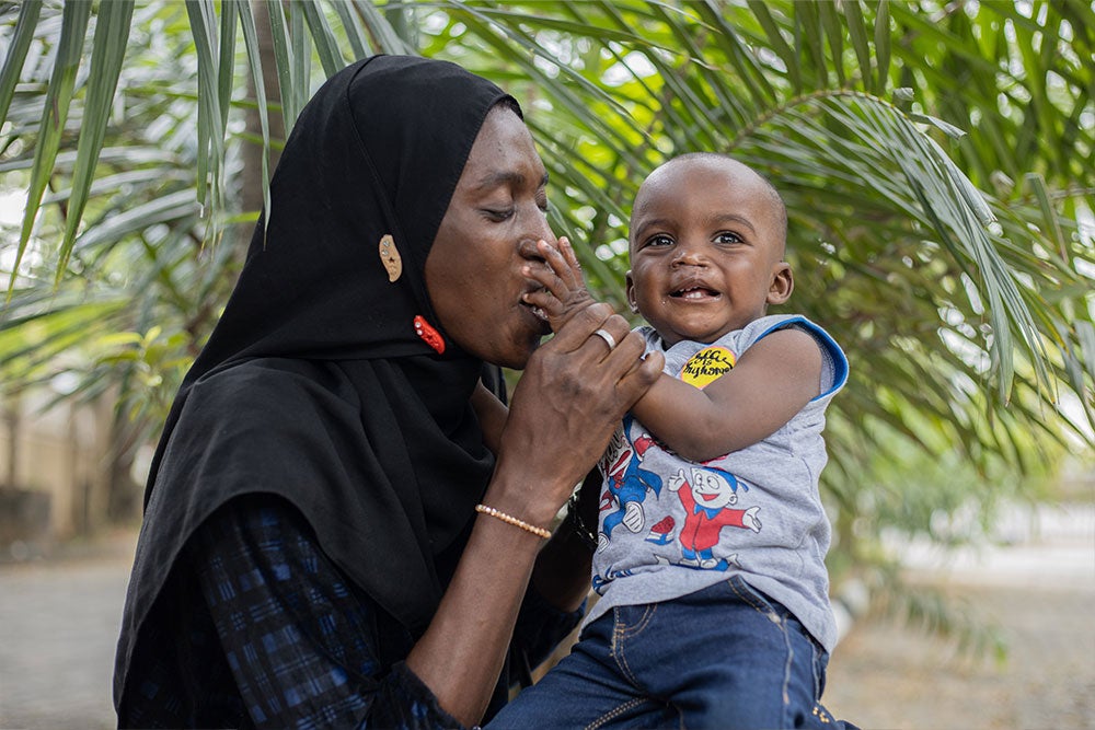 Olanike smiling and kissing Muaz's hand after his cleft surgery