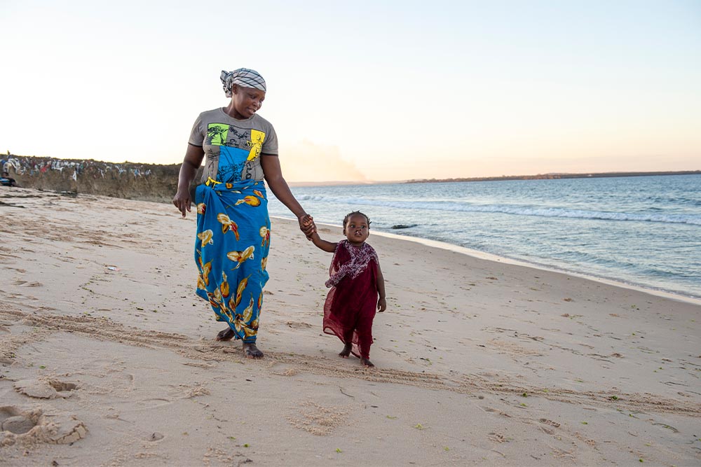 Anabela walking with Zena on the beach before her cleft surgery
