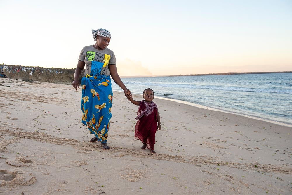 Anabela walking with Zena on the beach before her cleft surgery