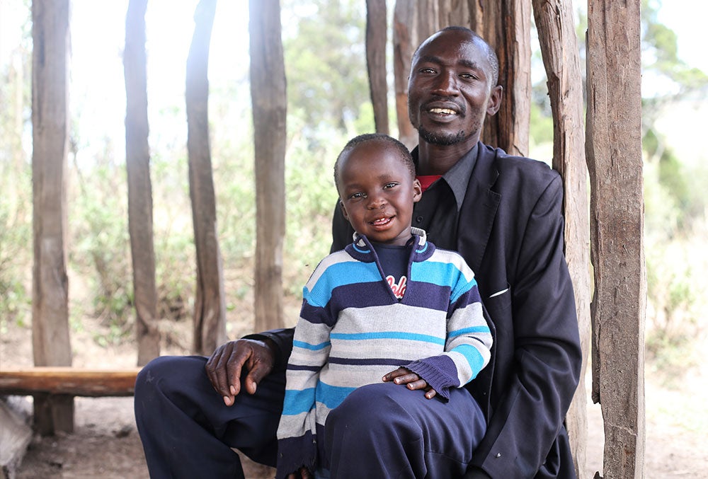 Benjamin smiling and sitting in his father's lap after cleft surgery