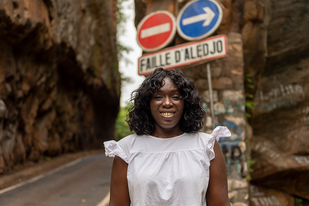 Dr. Nina Capo-Chichi smiling and standing at the crossroads at Faille D'Aledjo, Togo