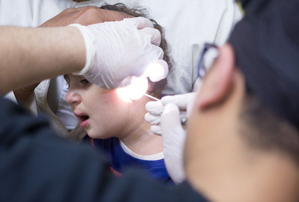 Dr. Tarek using an otoscope on a cleft-affected patient