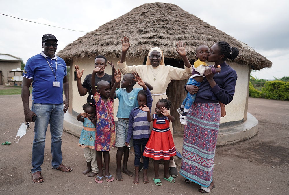 Kellen smiling and holding Eric with her family and Sister Liliana Najjuka after his cleft surgery