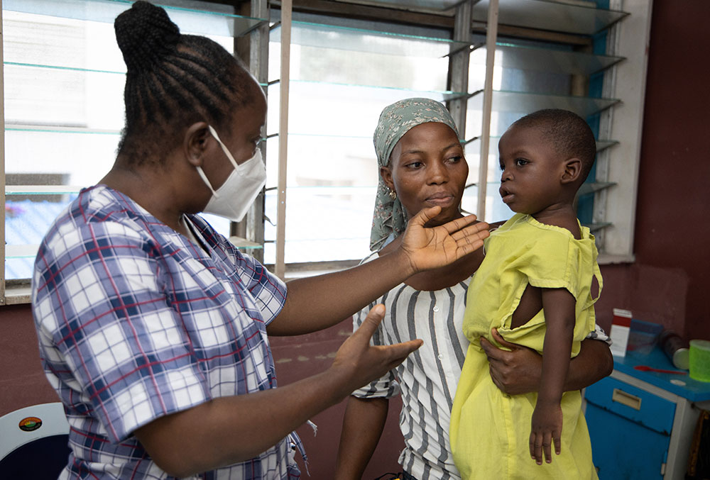 Nurse giving Opeyemi a health screening before cleft surgery