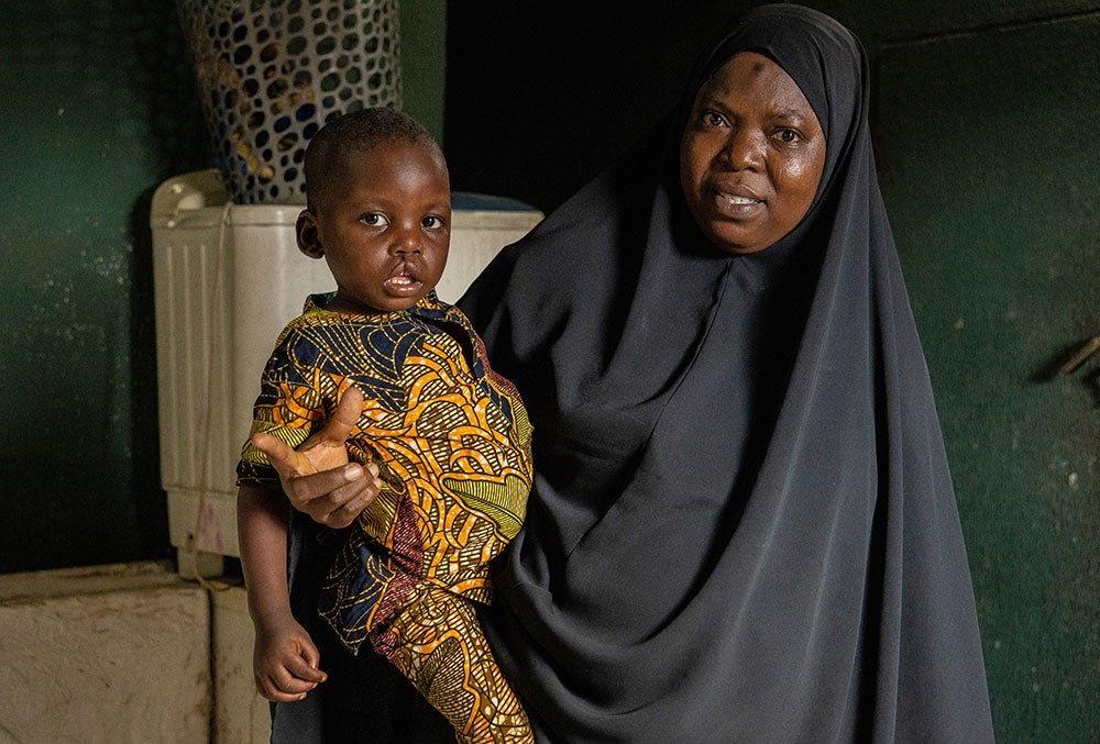 Opeyemi sitting on his grandmother's lap before cleft surgery