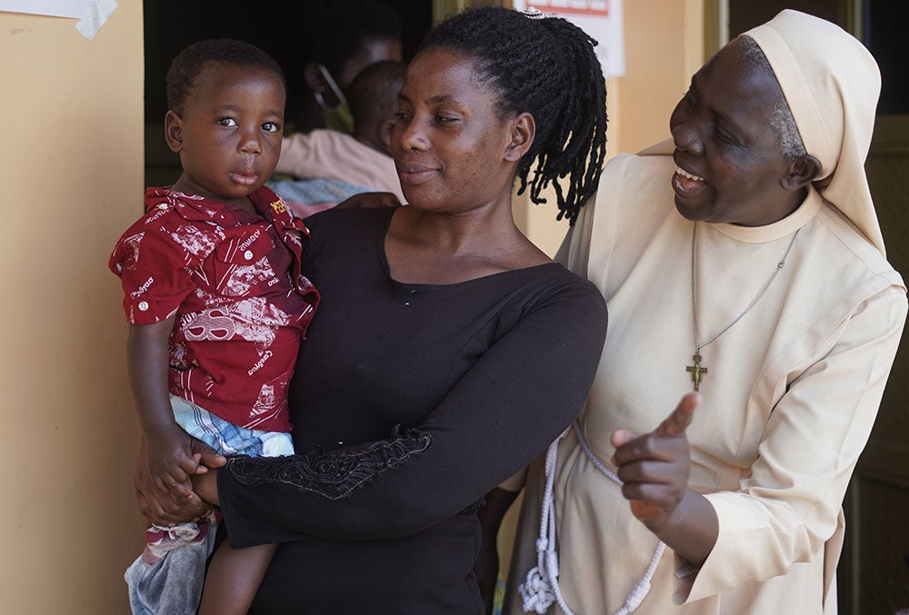 Sister Dr. Liliana Najjuka smiling with a patient and their mother after cleft surgery