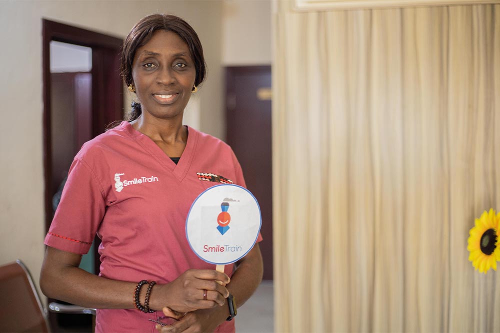 Dr. Adeola Olusanya smiling and holding a Smile Train sign