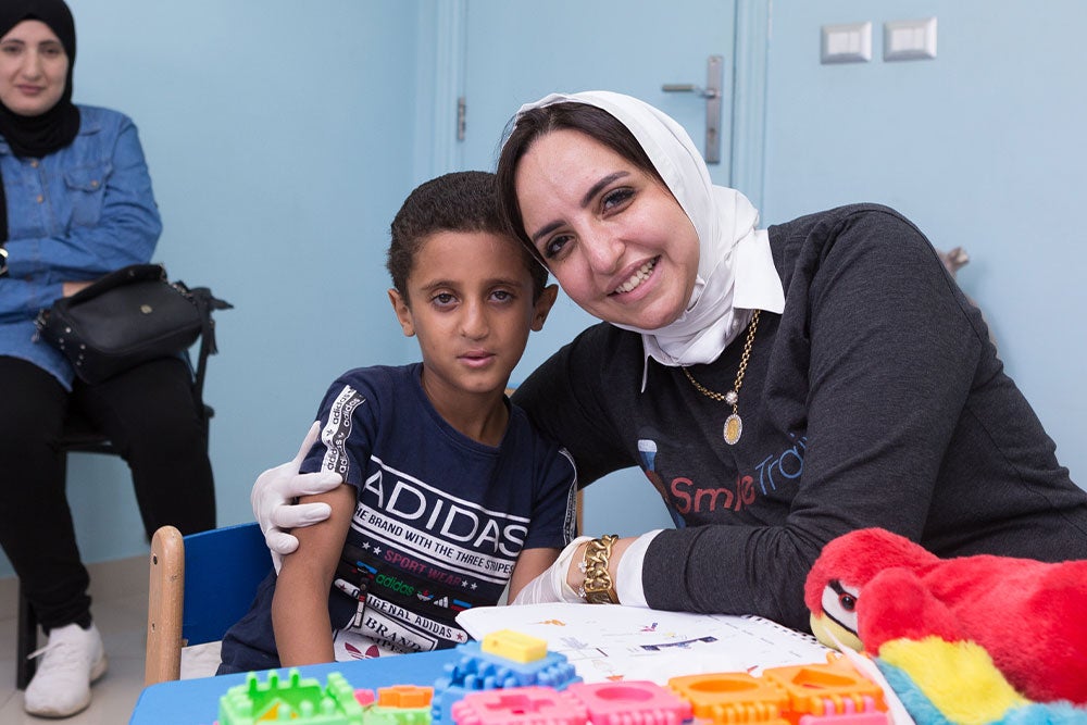 Dr. Sally smiling and hugging Fares