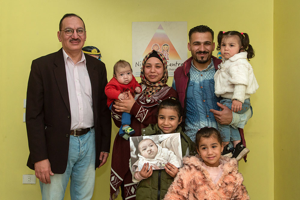 Mustafa avec sa famille tenant une photo de lui avant une opération de fente