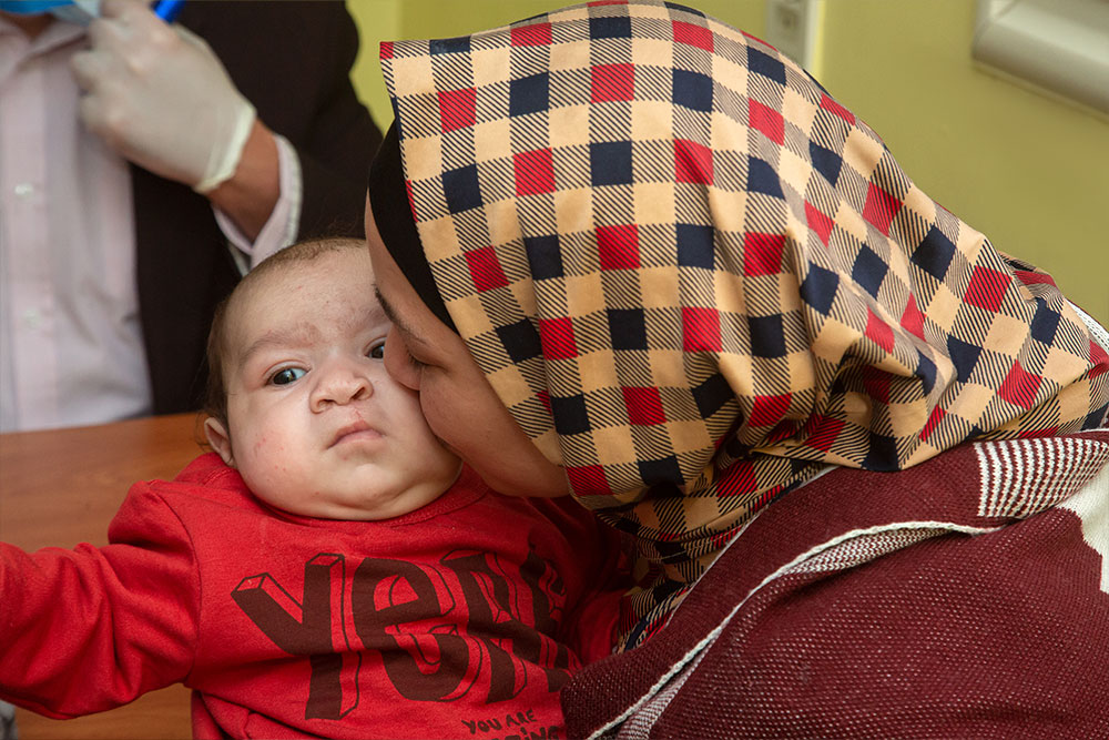 Nagla holding and kissing Mustafa after cleft surgery