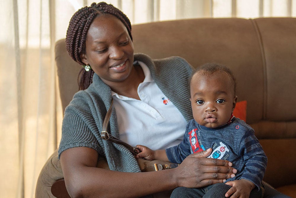 Yona smiling and holding a cleft-affected baby after their surgery