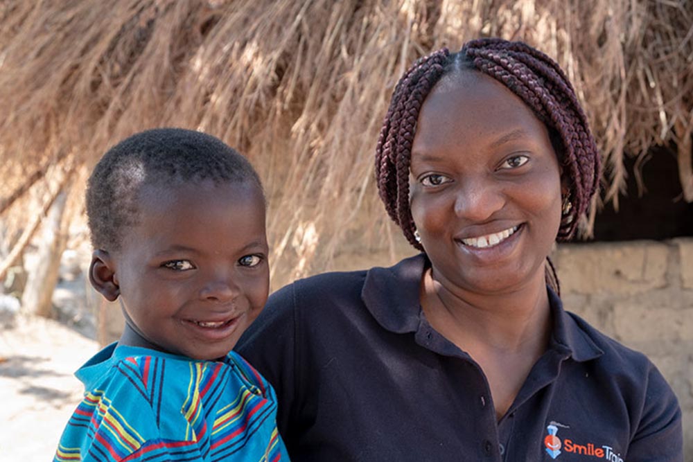 Yona smiling and holding a cleft-affected child after their surgery