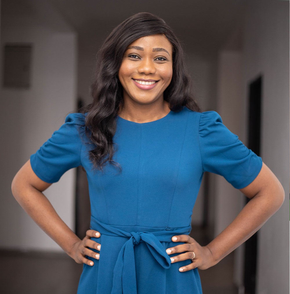 Dr. Oti standing and smiling with her hands on her hips