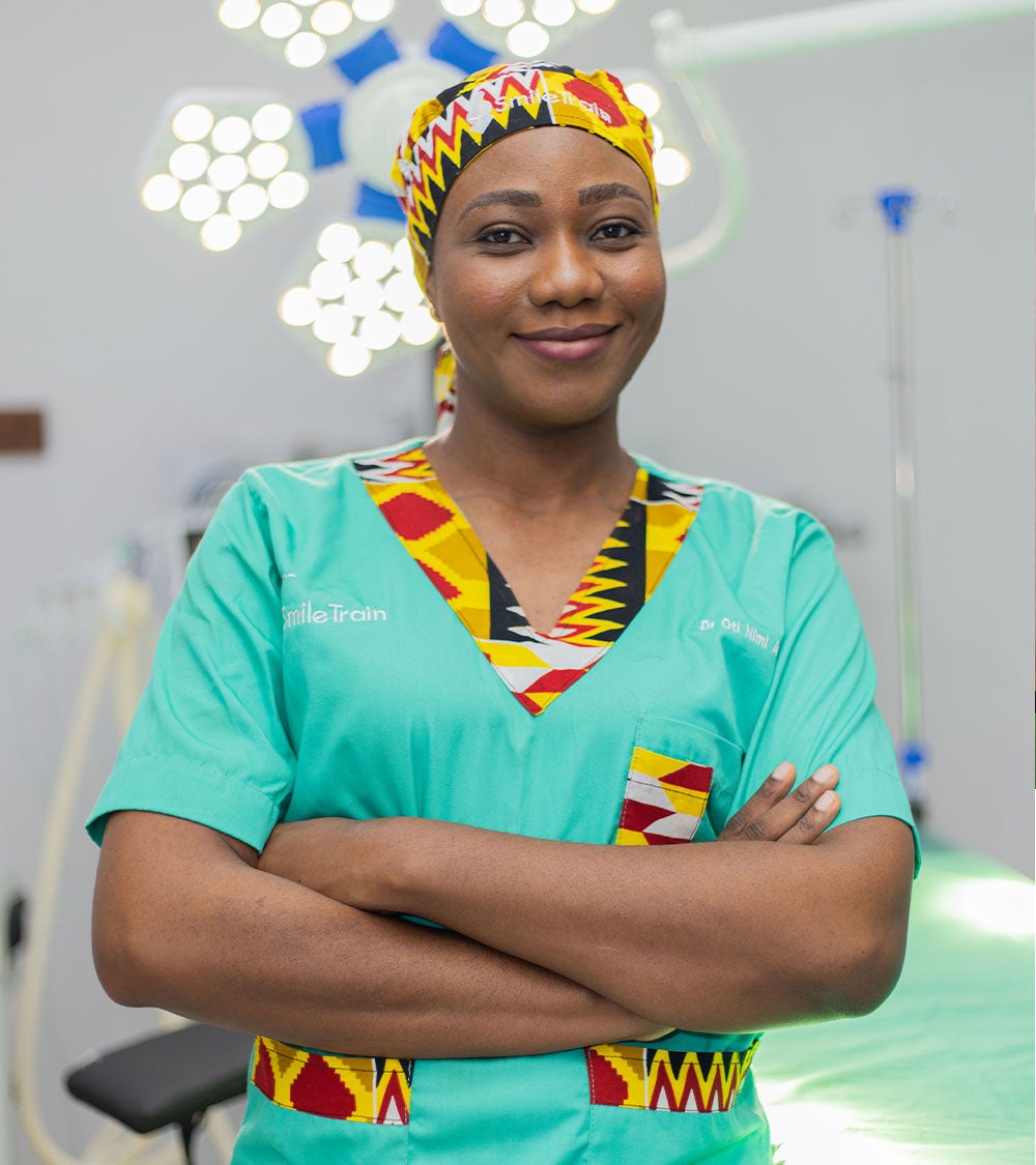 Dr. Oti smiling in scrubs with her arms crossed