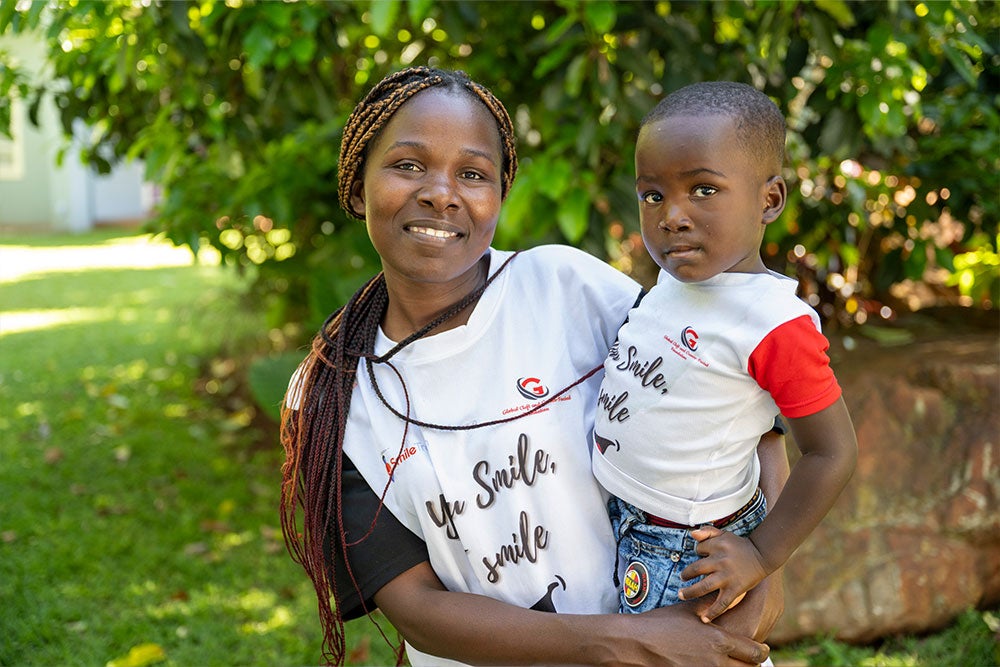 Sophia smiling and holding her son Takudzwa after his cleft surgery