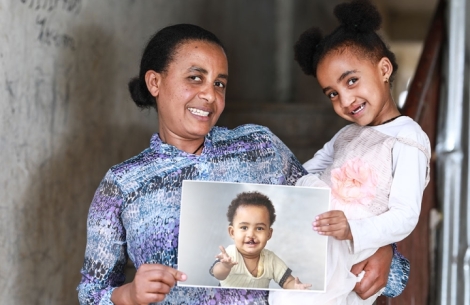 Marsillas and her mother Zinash smiling and holding a picture of herself before cleft surgery