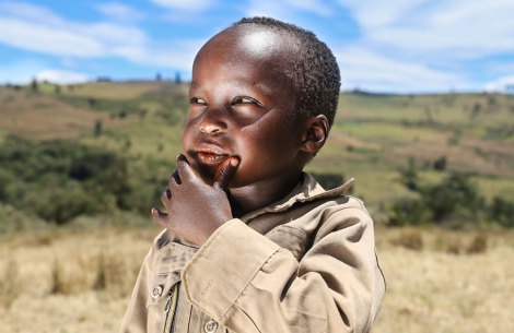 Benjamin thinking outside with his hand on his chin after cleft surgery