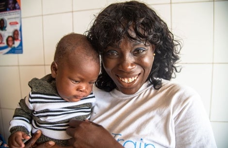 Dr. Nina Capo-Chichi smiling and holding a cleft-affected baby after their cleft surgery