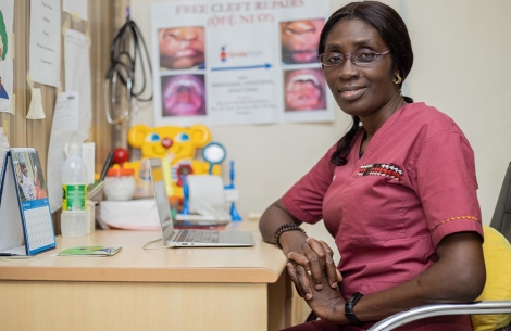 Dr. Adeola Olusanya smiling and sitting at her desk