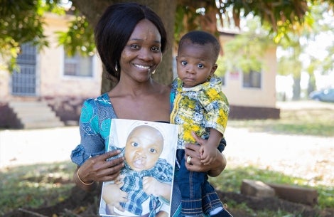 Favour and Annointed smiling and holding a picture of him before cleft surgery