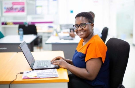 Veronica Kamwela smiling and using her laptop