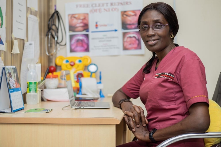 Dr. Adeola Olusanya smiling and sitting at her desk