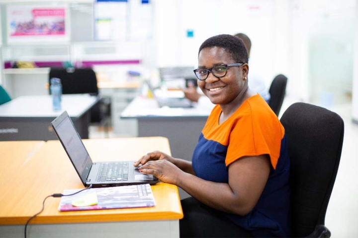 Veronica Kamwela souriante et utilisant son ordinateur portable