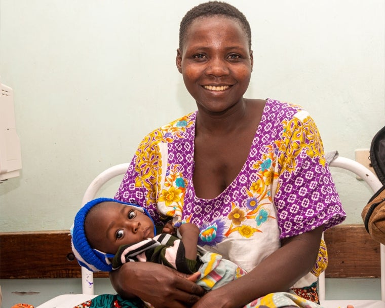 Mother smiling and feeding cleft-affected baby