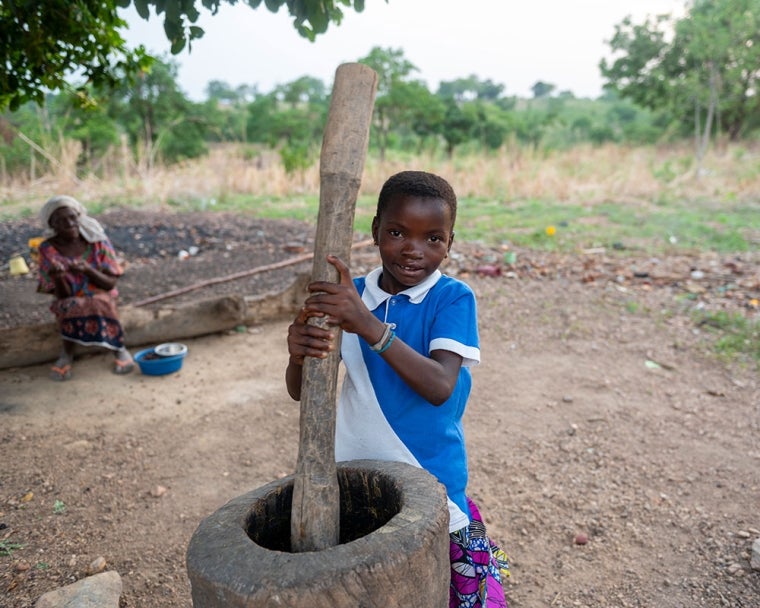 Akuya smiling and grinding a mortar and pestly after cleft surgery