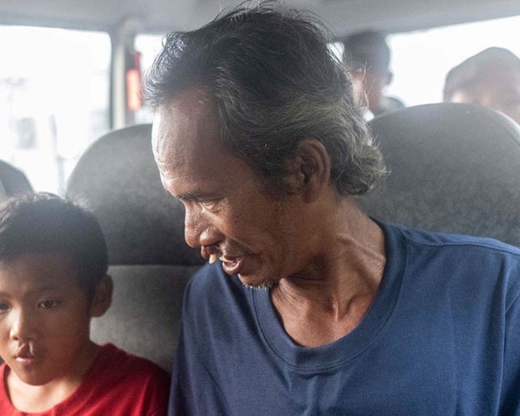Alim souriant et assis à côté de Rajib dans une fourgonnette
