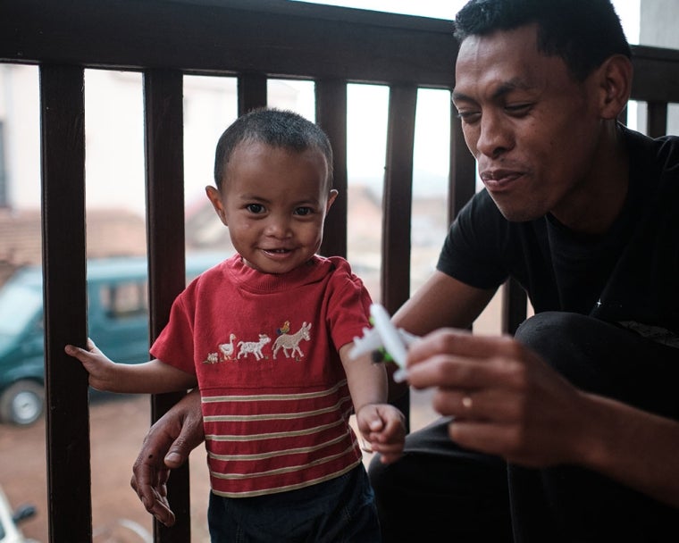 Eden smiling with his father Heriniaina and playing with a toy plane after cleft surgery