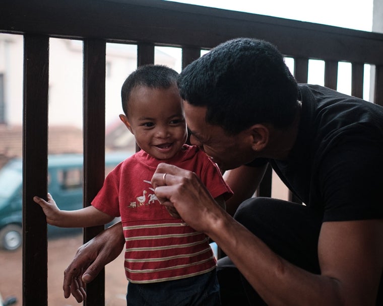 Eden smiling with his father Heriniaina and playing with a toy plane after cleft surgery